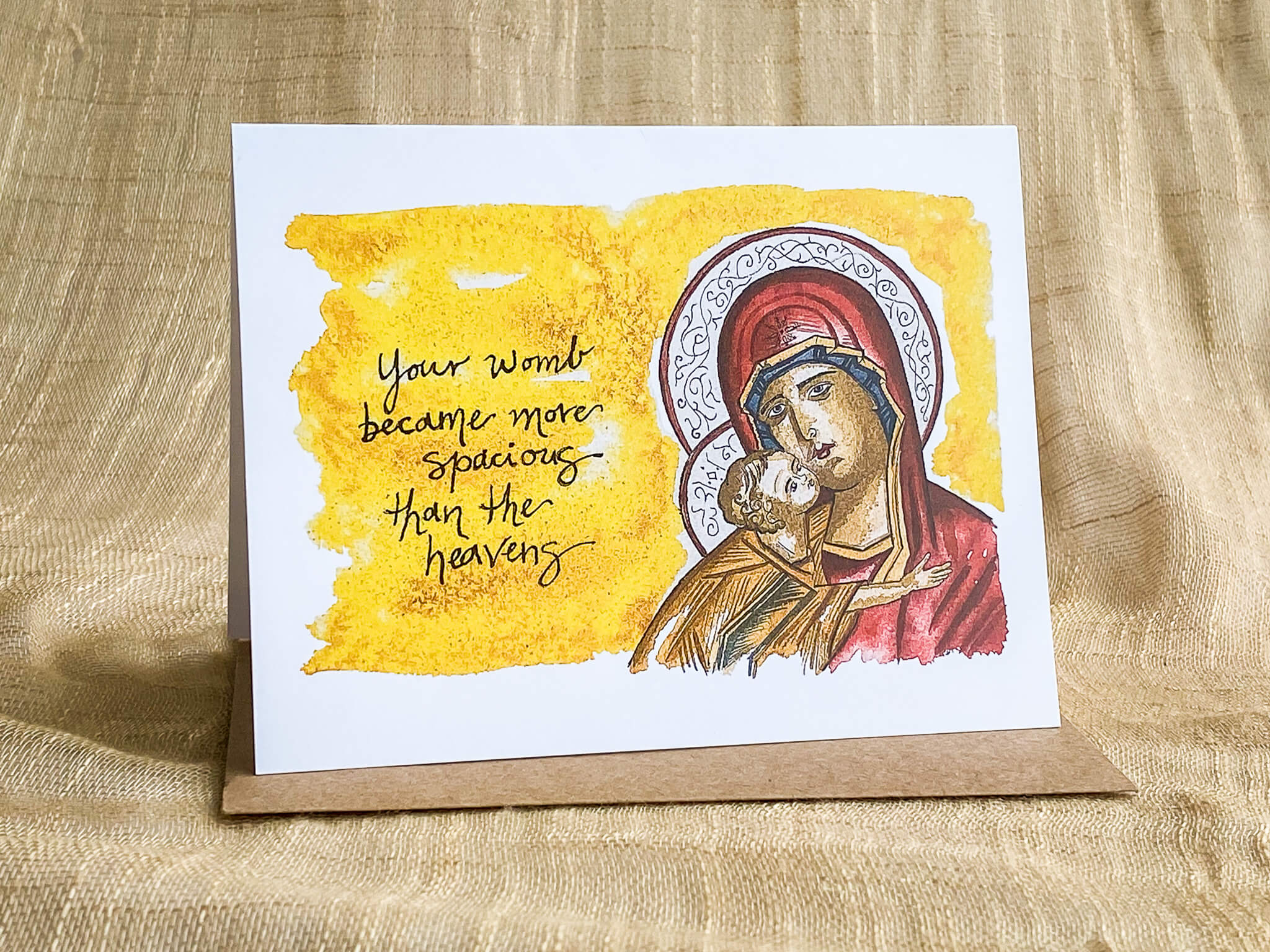 Orthodox greeting card by Katrina Dawn featuring a hand-painted icon of the Theotokos and Christ Child with gold halos, inscribed 'Your womb became more spacious than the heavens,' shown with a kraft paper envelope
