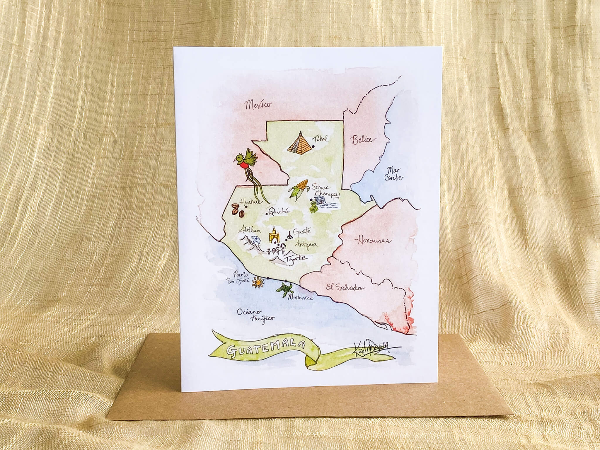 Illustrated watercolor map greeting card of Guatemala by Katrina Dawn, featuring hand-lettered landmarks like Tikal, Antigua, Lake Atitlán, and Semuc Champey, shown with a kraft paper envelope.