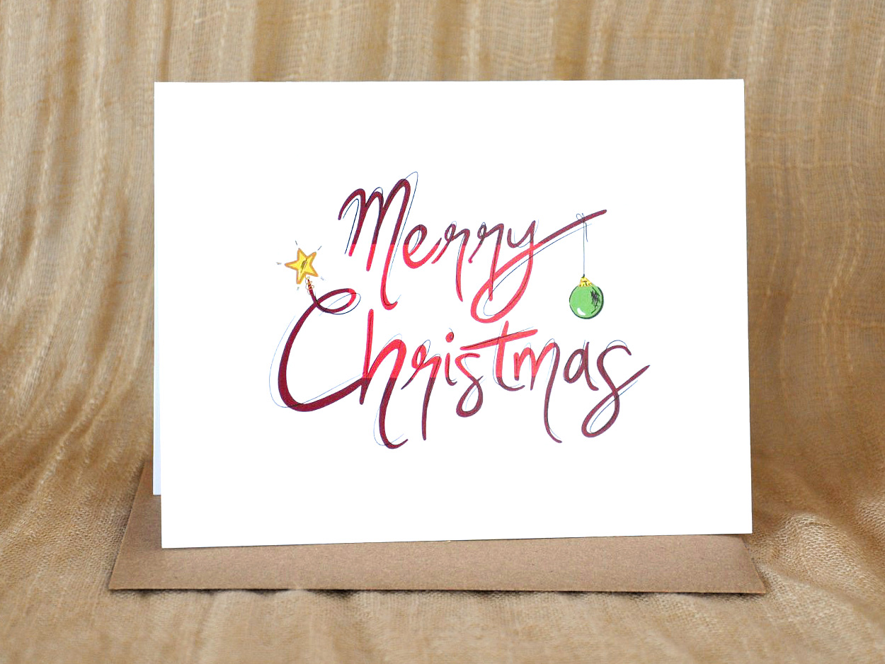 KatrinaDawn 'Merry Christmas' hand-lettered greeting card, shown with a kraft paper envelope.